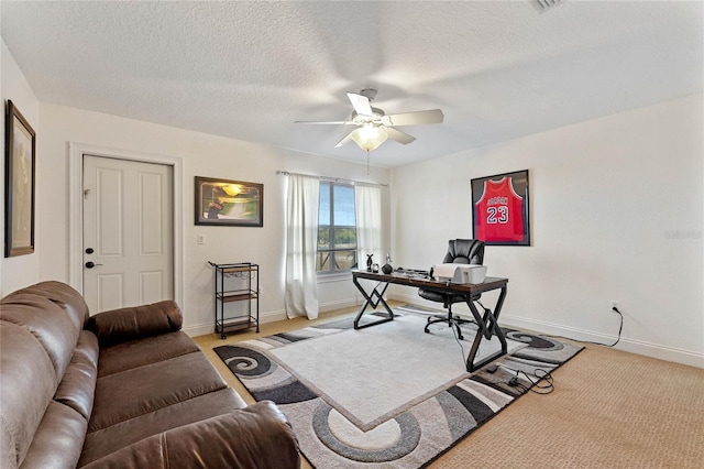carpeted home office with ceiling fan and a textured ceiling