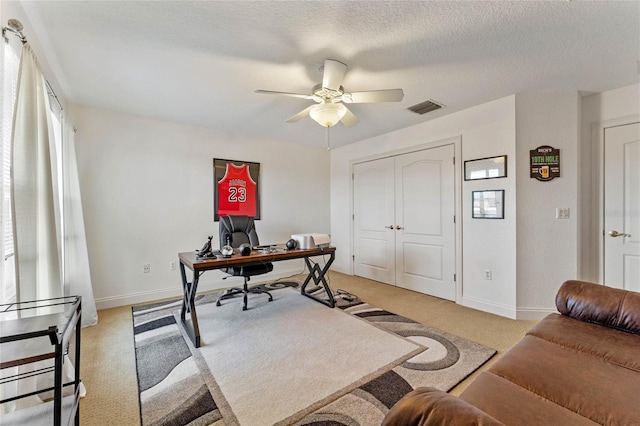 office space featuring ceiling fan, light carpet, and a textured ceiling