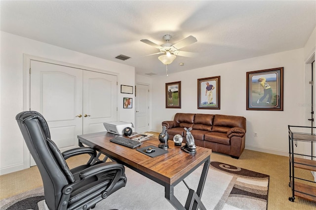 carpeted office space with a textured ceiling and ceiling fan