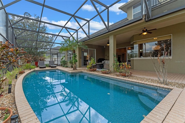 view of swimming pool with a patio area, ceiling fan, and glass enclosure