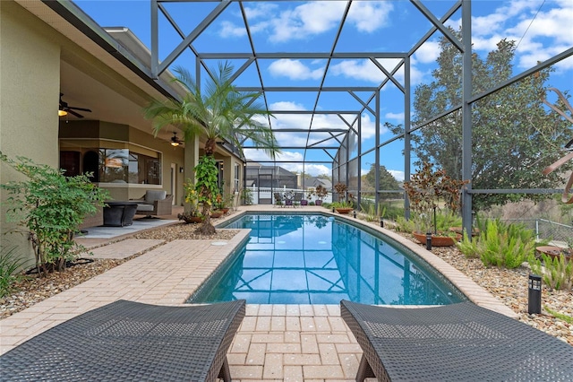 view of pool with a patio area, ceiling fan, and glass enclosure