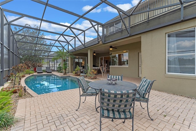 view of swimming pool with glass enclosure, ceiling fan, and a patio area