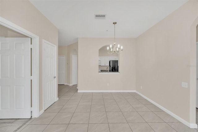 empty room featuring an inviting chandelier and light tile patterned floors