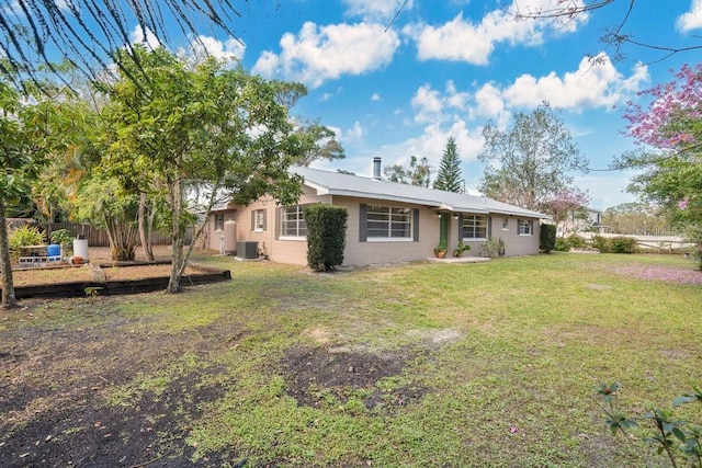 back of property featuring central AC, fence, and a lawn