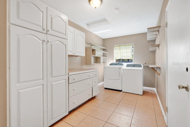 laundry area featuring light tile patterned floors, a textured ceiling, baseboards, cabinet space, and washer and clothes dryer