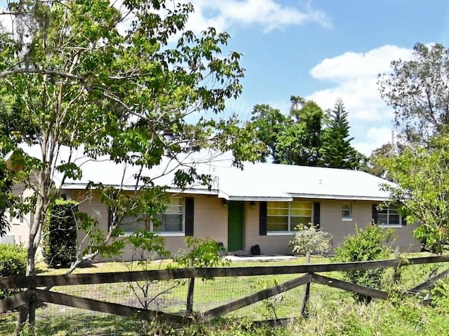ranch-style home featuring concrete block siding and a fenced front yard