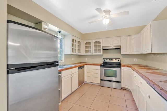 kitchen featuring under cabinet range hood, white cabinetry, glass insert cabinets, and stainless steel appliances