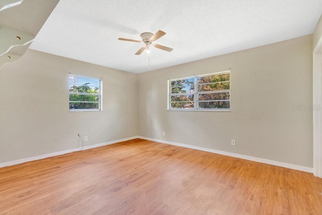empty room featuring a textured ceiling, baseboards, wood finished floors, and ceiling fan