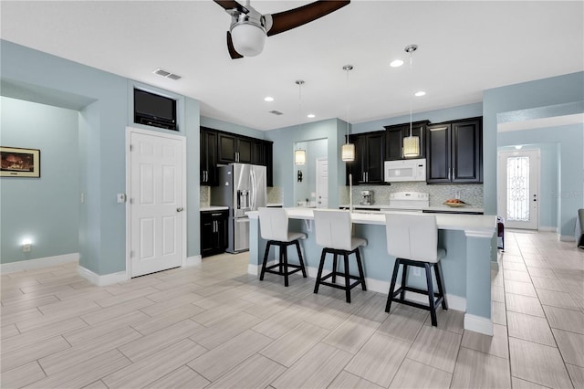 kitchen with stainless steel fridge with ice dispenser, decorative light fixtures, a breakfast bar area, and a center island with sink