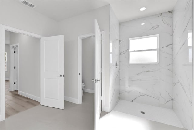 bathroom with a tile shower, wood-type flooring, and toilet