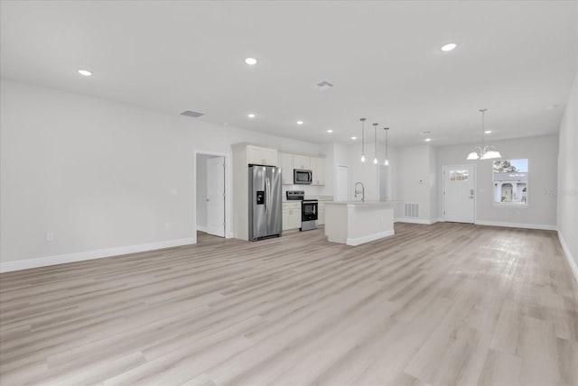 unfurnished living room featuring a notable chandelier, sink, and light wood-type flooring