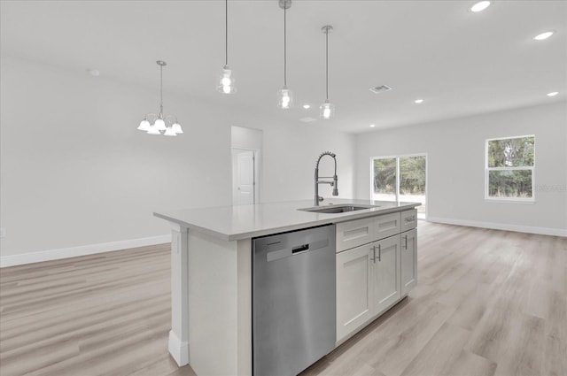 kitchen featuring sink, a kitchen island with sink, white cabinets, decorative light fixtures, and stainless steel dishwasher