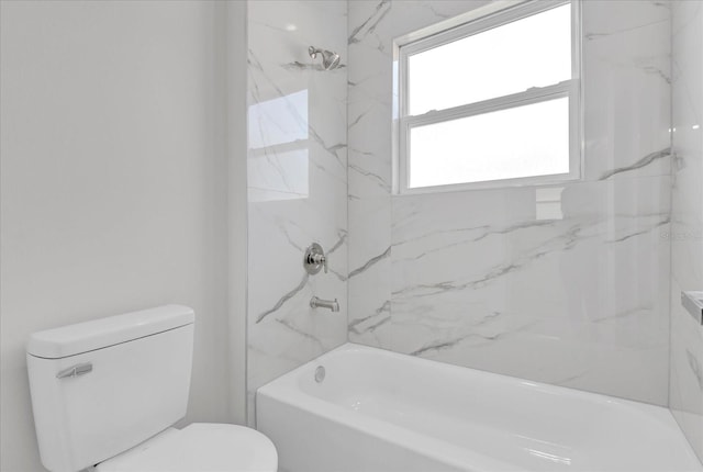 bathroom featuring toilet and tiled shower / bath