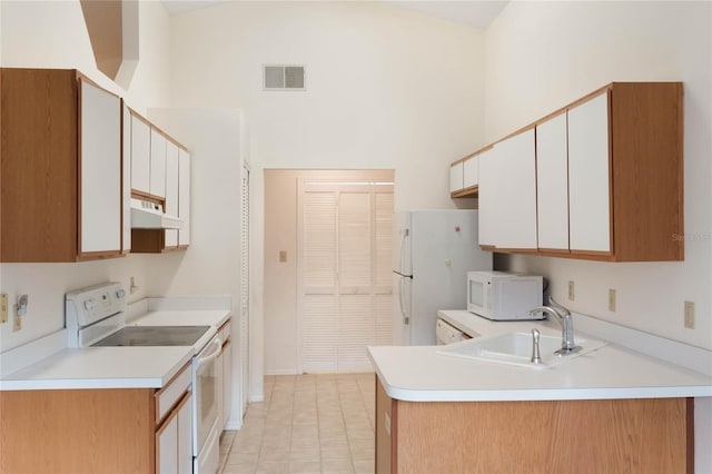 kitchen featuring sink, white cabinets, a high ceiling, light tile patterned floors, and white appliances