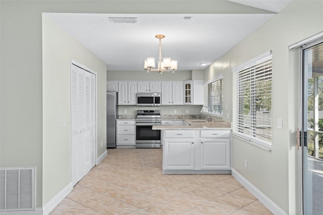 kitchen featuring decorative light fixtures, white cabinetry, sink, a notable chandelier, and stainless steel appliances