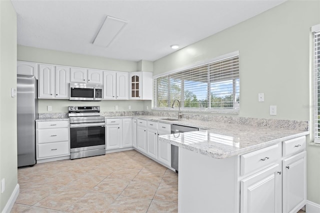 kitchen featuring light tile patterned flooring, appliances with stainless steel finishes, sink, white cabinets, and kitchen peninsula