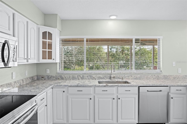 kitchen featuring appliances with stainless steel finishes, light stone countertops, sink, and white cabinets