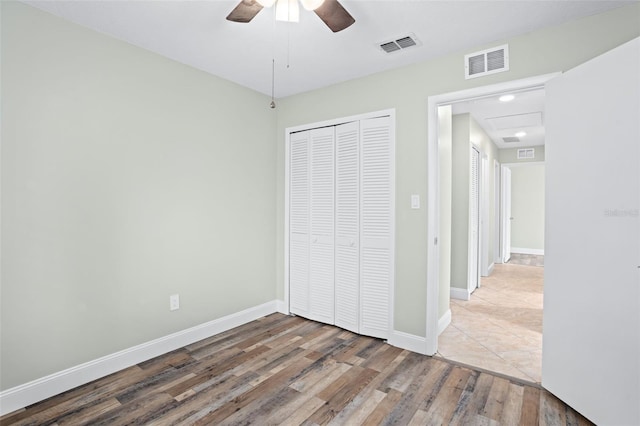 unfurnished bedroom with hardwood / wood-style flooring, ceiling fan, and a closet