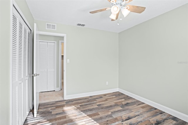 unfurnished bedroom with dark wood-type flooring, ceiling fan, and a closet