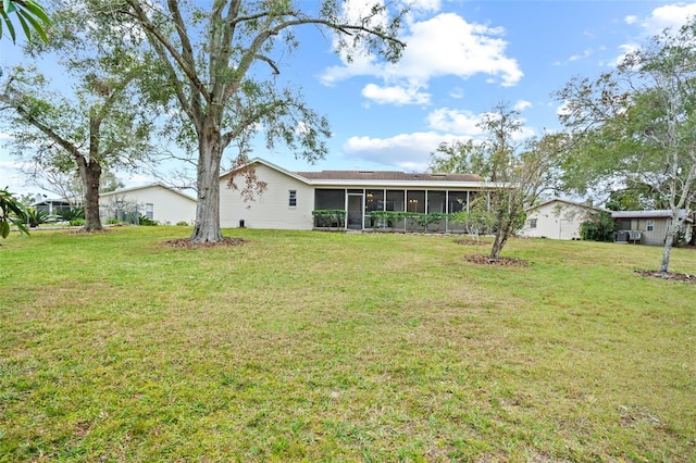 back of property with a sunroom and a lawn