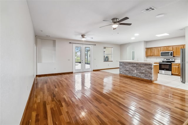 unfurnished living room with french doors, ceiling fan, and light wood-type flooring