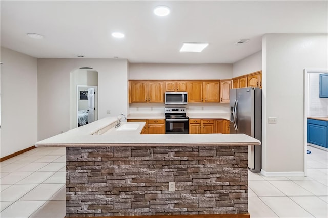 kitchen featuring stainless steel appliances, light tile patterned flooring, sink, and an island with sink