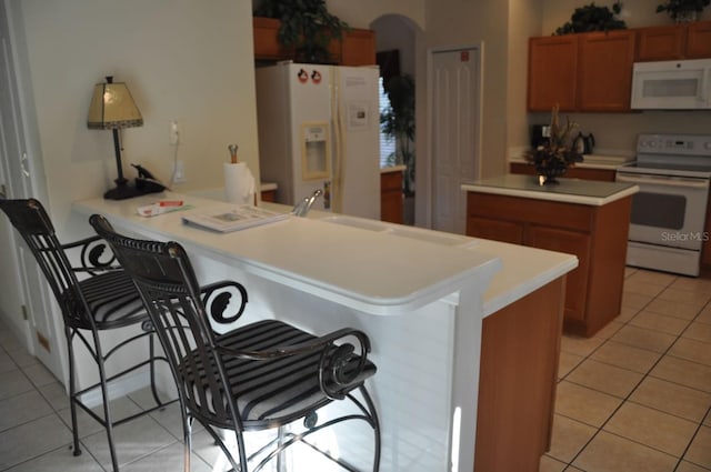 913 Henley Cir, Davenport, FL 33896 - kitchen featuring light tile patterned floors, white appliances, a breakfast bar, and kitchen peninsula