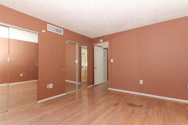 626 Orange Dr Unit 242, Altamonte Springs, FL 32701 - unfurnished bedroom featuring a textured ceiling, light hardwood / wood-style floors, and multiple closets