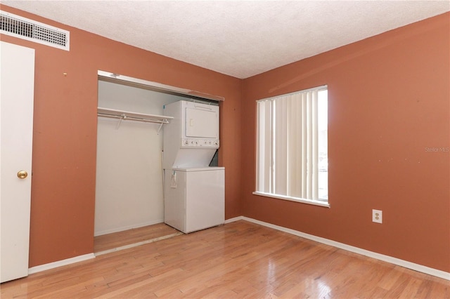 626 Orange Dr Unit 242, Altamonte Springs, FL 32701 - clothes washing area with stacked washing maching and dryer, hardwood / wood-style floors, and a textured ceiling