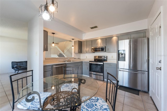 kitchen featuring pendant lighting, sink, appliances with stainless steel finishes, gray cabinetry, and light tile patterned flooring