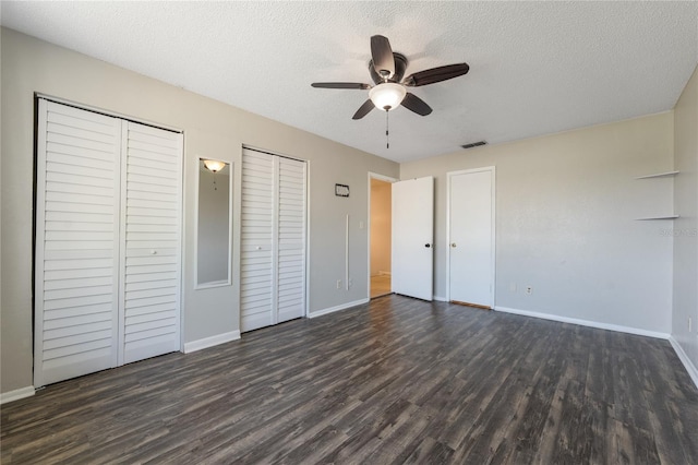 unfurnished bedroom with multiple closets, ceiling fan, dark hardwood / wood-style floors, and a textured ceiling