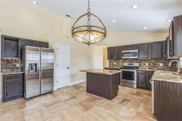 kitchen with a kitchen island, appliances with stainless steel finishes, decorative light fixtures, sink, and light stone counters