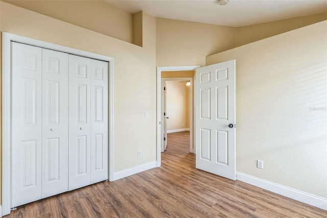 unfurnished bedroom with hardwood / wood-style flooring, vaulted ceiling, and a closet