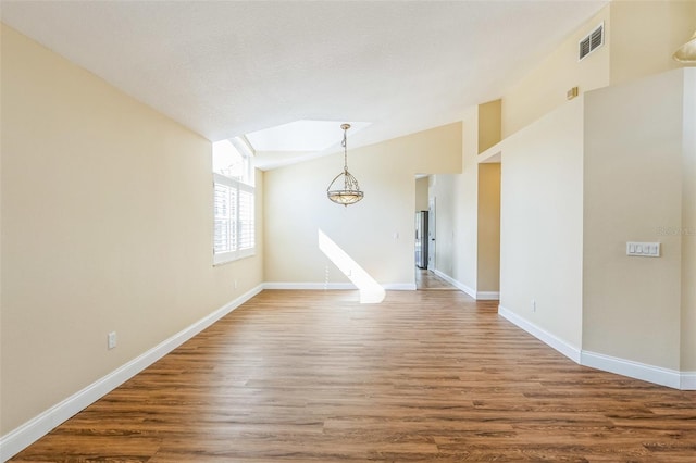 unfurnished room with an inviting chandelier, hardwood / wood-style flooring, vaulted ceiling, and a textured ceiling