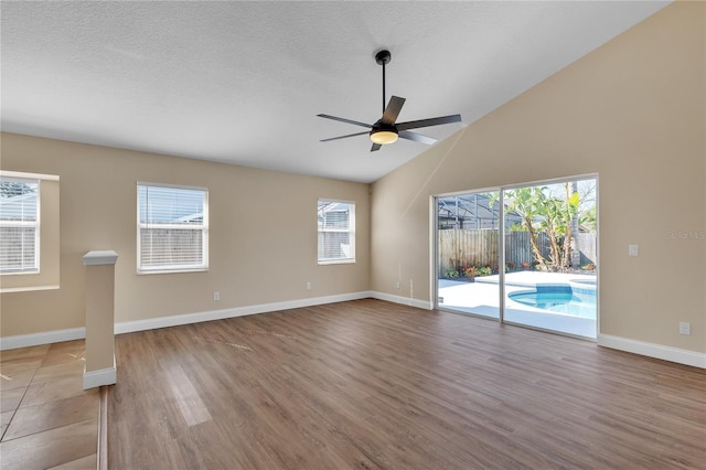 unfurnished living room featuring vaulted ceiling, ceiling fan, light hardwood / wood-style floors, and a textured ceiling