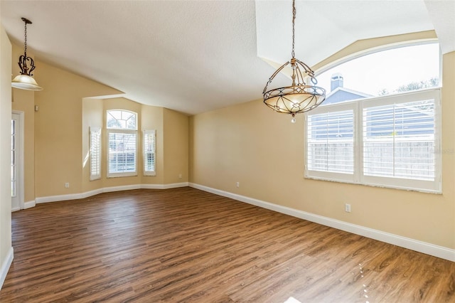 empty room featuring vaulted ceiling, wood-type flooring, and a textured ceiling