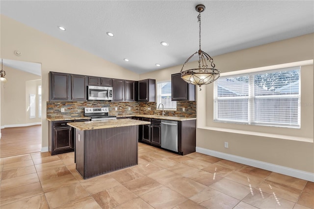 kitchen featuring tasteful backsplash, vaulted ceiling, appliances with stainless steel finishes, a kitchen island, and pendant lighting