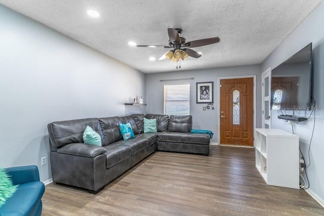 living room featuring ceiling fan, wood-type flooring, and a textured ceiling