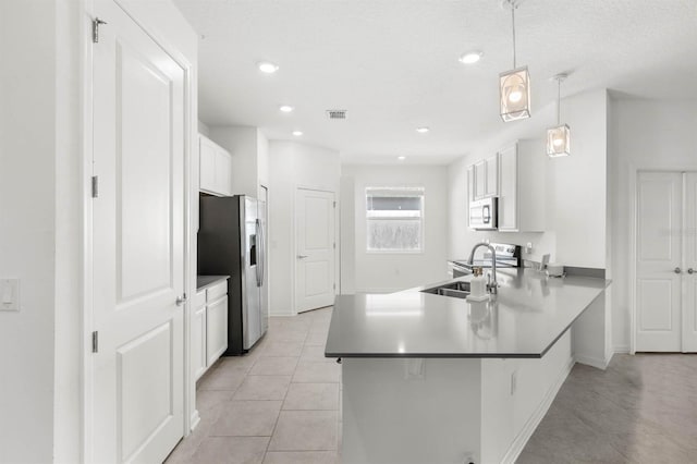 kitchen with decorative light fixtures, stainless steel appliances, white cabinetry, and kitchen peninsula