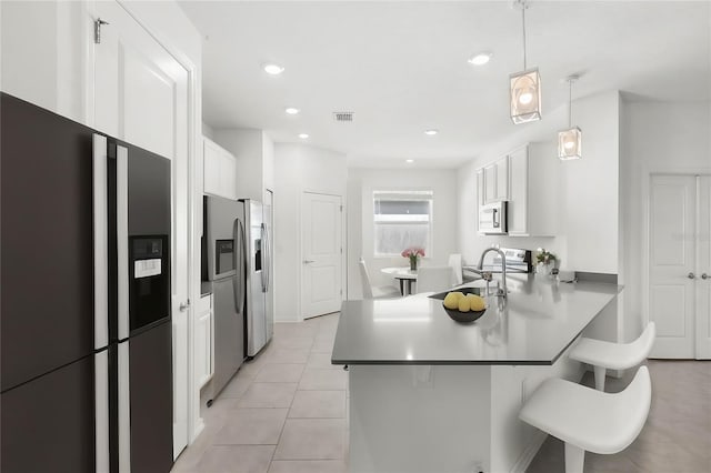 kitchen with appliances with stainless steel finishes, a kitchen breakfast bar, kitchen peninsula, white cabinets, and hanging light fixtures