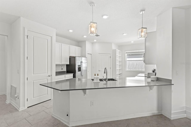 kitchen featuring white cabinets, decorative light fixtures, stainless steel fridge with ice dispenser, and kitchen peninsula