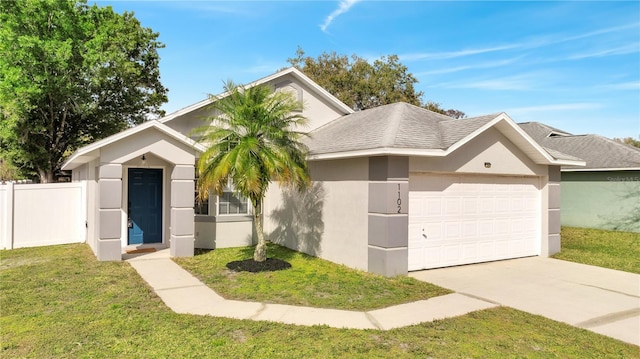 view of front facade with a garage, fence, concrete driveway, stucco siding, and a front yard