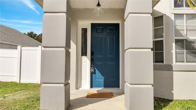 view of exterior entry featuring fence and stucco siding