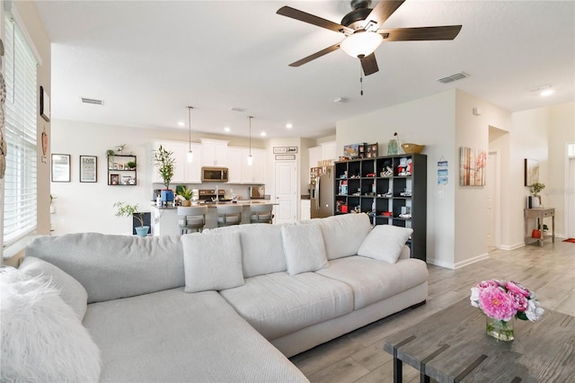 living room featuring ceiling fan and light hardwood / wood-style flooring