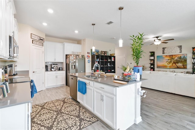 kitchen with white cabinets, an island with sink, stainless steel appliances, and sink