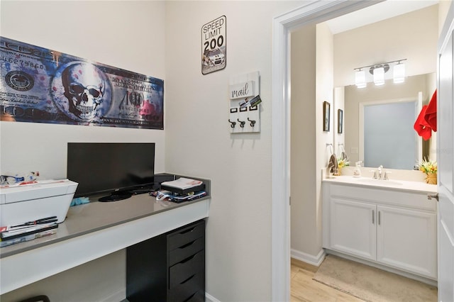 office area with light wood-type flooring and sink