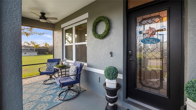 view of exterior entry featuring ceiling fan and stucco siding