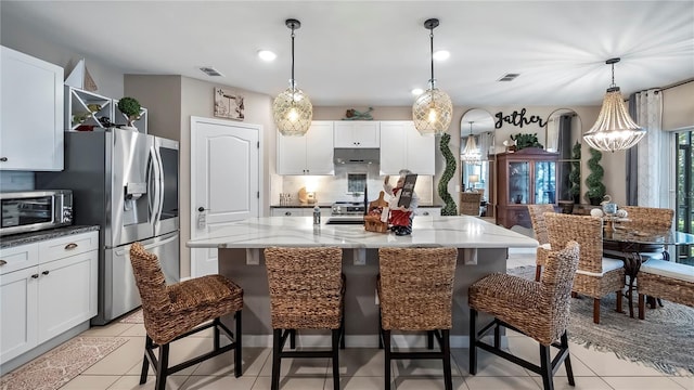 kitchen with appliances with stainless steel finishes, a breakfast bar, decorative light fixtures, and an island with sink