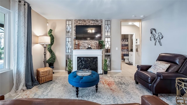 living area featuring light tile patterned floors, a fireplace, baseboards, and plenty of natural light