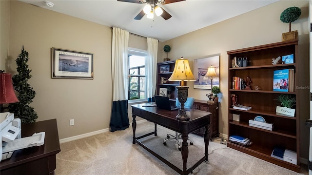 office space featuring light carpet, ceiling fan, and baseboards